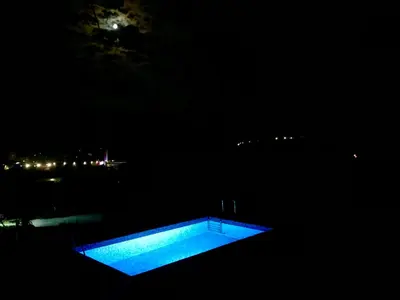 a swimming pool at night with the moon in the sky at Etno selo Stanojevic in Boljevac