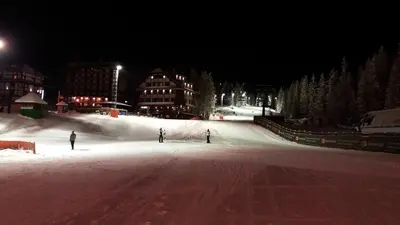 two people skiing down a snow covered slope at night at Apartment Dunja Konaci in Kopaonik