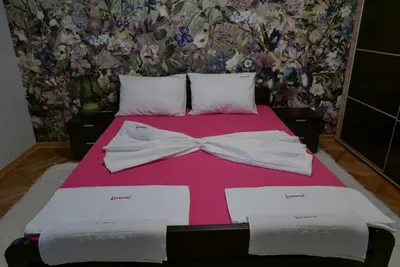 a bed with a pink bedspread with a bow tie on it at Apartment Zavičaj in Vrnjačka Banja