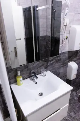 a bathroom with a white sink and a shower at SPA Apartment Nalis in Niš