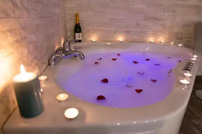 a bath tub with hearts in it with candles and a bottle of wine at SPA Apartment Nalis in Niš