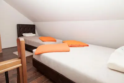a room with two beds with orange pillows on them at Prenoćište Kovač in Vranje