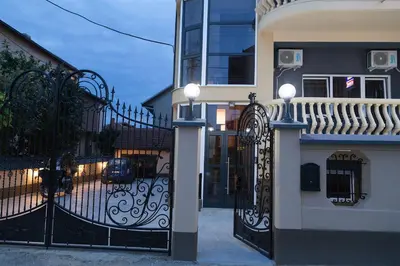 a house with a black gate with a car on the street at Prenoćište Kovač in Vranje