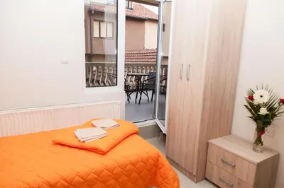 a bedroom with an orange bed and a balcony at Prenoćište Kovač in Vranje