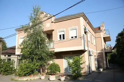 a pink house with trees in front of it at Apartments Lukic in Vrnjačka Banja