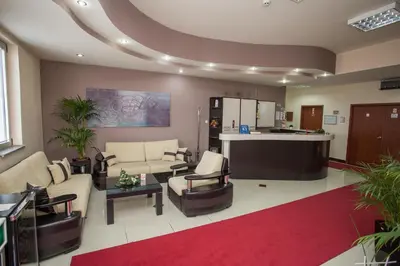 a living room with couches and chairs and a kitchen at Sin-Kom Hotel Garni in Pirot
