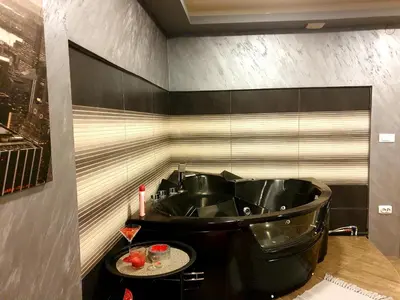 a bathroom with a black tub and a table at Ceca Apartman in Niš
