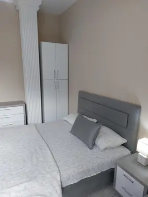 a bedroom with a white bed with a gray pillow at Apartmani Radulović in Vrnjačka Banja