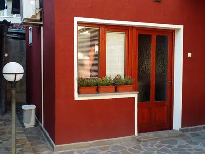 a red building with a window with potted plants at Apartman Ristic in Niška Banja