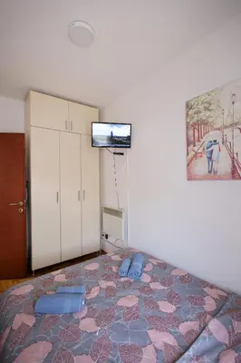 a bedroom with a bed and a tv on the wall at Apartman Lena in Vrnjačka Banja