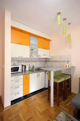a kitchen with orange and white cabinets and a table at Apartman Lena in Vrnjačka Banja