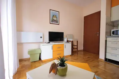 a living room with a table and a kitchen at Apartman Lena in Vrnjačka Banja