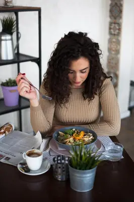 a woman sitting at a table with a bowl of food at Hotel 