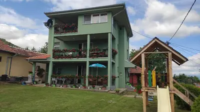 a green house with flowers on the balcony at Apartment Pavlovic in Soko Banja