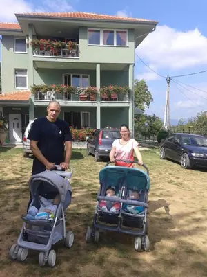 a man and a woman standing next to two strollers at Apartment Pavlovic in Soko Banja