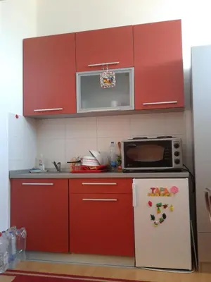 a kitchen with red cabinets and a microwave and a refrigerator at Studio Pinos in Soko Banja
