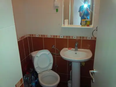 a person taking a picture of a bathroom with a toilet and sink at Studio Pinos in Soko Banja