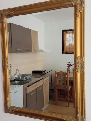 a mirror reflecting a kitchen with a sink and a table at Apartman Anđelina Vrnjačka Banja in Vrnjačka Banja