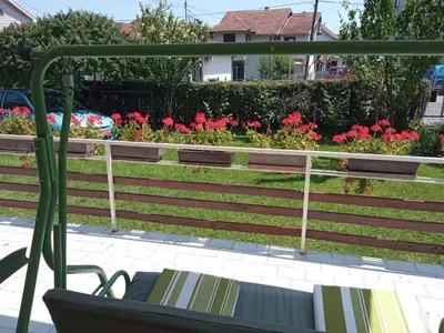 a bench in front of a garden with red flowers at Apartman Anđelina Vrnjačka Banja in Vrnjačka Banja