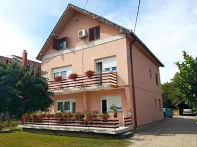 a pink house with flower boxes on the balcony at Apartman Anđelina Vrnjačka Banja in Vrnjačka Banja