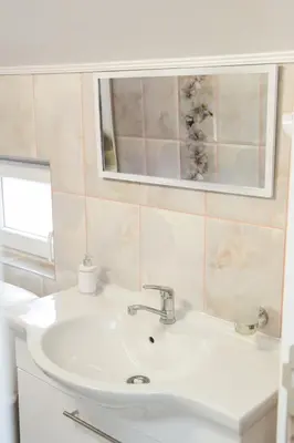 a bathroom with a white sink and a mirror at Apartmani 