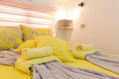 a yellow bed with towels and pillows on it at Apartmani 