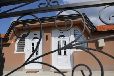 a house with a white door behind a fence at Apartmani 