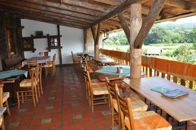 a restaurant with wooden tables and chairs and a view at Inn Cakmara in Raška