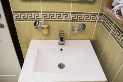 a bathroom with a white sink and two faucets at Apartment Aleksija in Niš