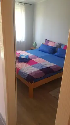 a bedroom with a bed with blue and purple sheets at Apartmani V&F in Vrnjačka Banja