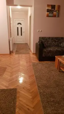 a living room with a black couch and a wooden floor at Apartmani V&F in Vrnjačka Banja