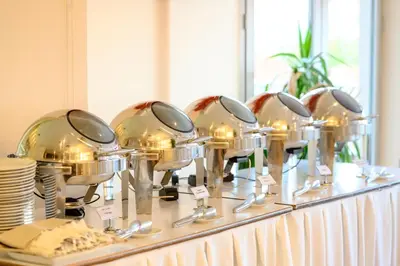 a buffet line with silver dishes and spoons at Hotel Tami Residence in Niš