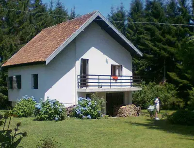 a large white house with a balcony in a yard at Planinska kuća Vladanka - planina Goč - banjska strana - preko puta ski staze in Biserske Kuće