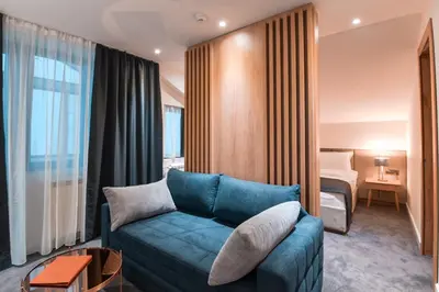a hotel room with a couch and a bed at Hotel Putnik Kopaonik in Kopaonik
