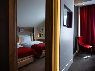 a hotel room with a bed and a red chair at Hotel Putnik Kopaonik in Kopaonik