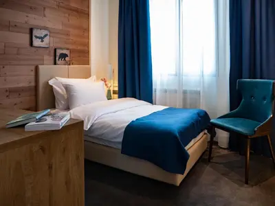 a bedroom with a bed and a blue chair at Hotel Putnik Kopaonik in Kopaonik
