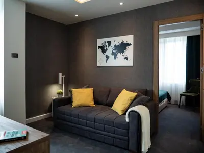a living room with a brown couch with yellow pillows at Hotel Putnik Kopaonik in Kopaonik