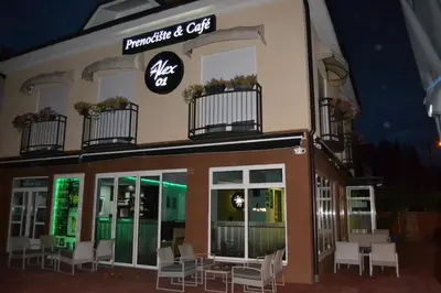 a restaurant with white chairs in front of a building at B&B Alex18 in Niš