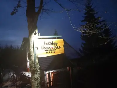 a sign on the side of a house with a tree at Apartments Holiday Home Srce in Kopaonik