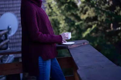 a woman standing on a bench holding a coffee cup at Apartments Holiday Home Srce in Kopaonik
