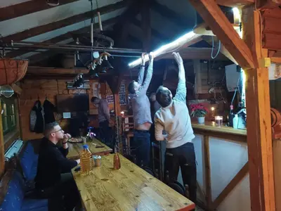 a group of men standing around a table in a bar at Kuca za odmor ''Djurovic'' in Kopaonik