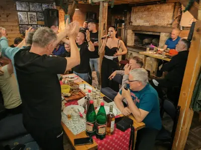 a group of people sitting at a table with their hands in the air at Kuca za odmor ''Djurovic'' in Kopaonik