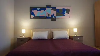 a bedroom with a large bed with two lamps on it at Apartments Tatjana in Jagodina