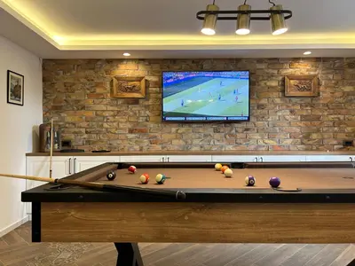 a pool table with a tv on a brick wall at Laguna Green Guest House in Niš