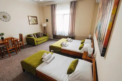 a hotel room with two beds and a living room at Laguna Green Guest House in Niš