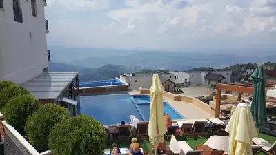 a hotel with a swimming pool and tables and umbrellas at K23 apartment Milmari in Kopaonik