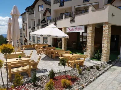 a restaurant with tables and umbrellas in front of a building at K22 Apartment Milmari in Kopaonik