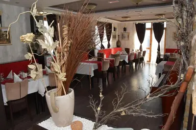 a dining room with tables and chairs and vases with flowers at K22 Apartment Milmari in Kopaonik