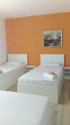 two white beds in a room with an orange wall at Rooms Ela Ela in Prekodolce
