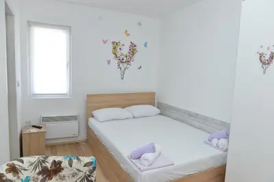 a white bedroom with a bed and a window at Rooms Ela Ela in Prekodolce
